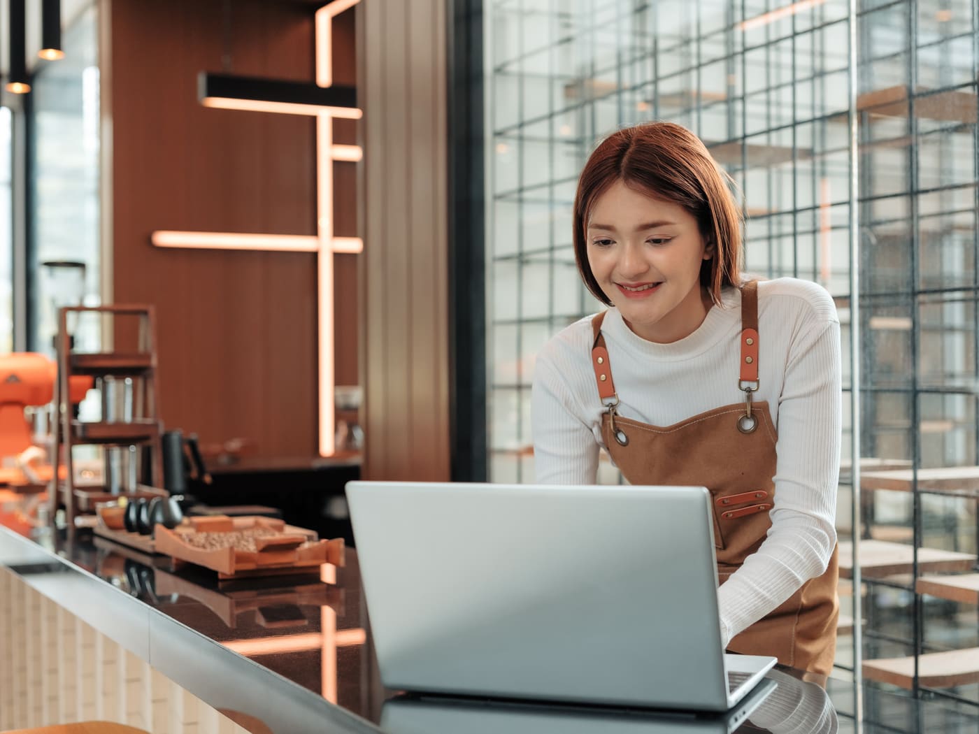 Café-Inhaberin pflegt ihren Online-Auftritt am Laptop im eigenen Laden